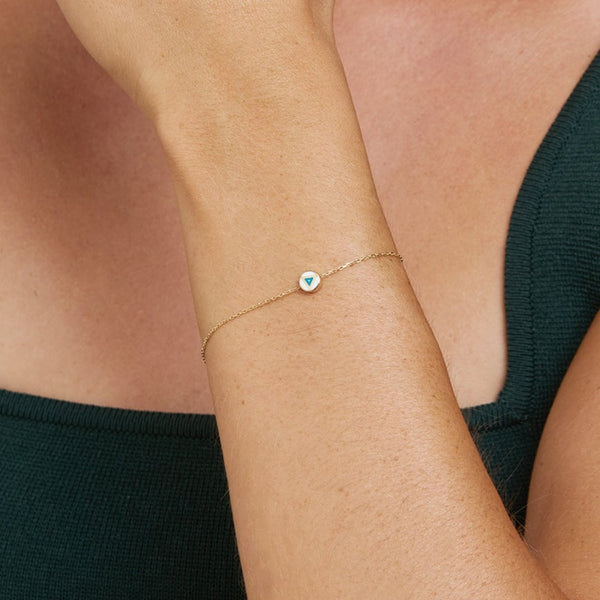 This handmade 14 karat gold bracelet is the perfect every day gold accessory. Its pendant features a hand-painted and two-sided enamel tribal painting symbol. The design allows the bracelet to move in anyway, always revealing its beautiful hand-painted side.